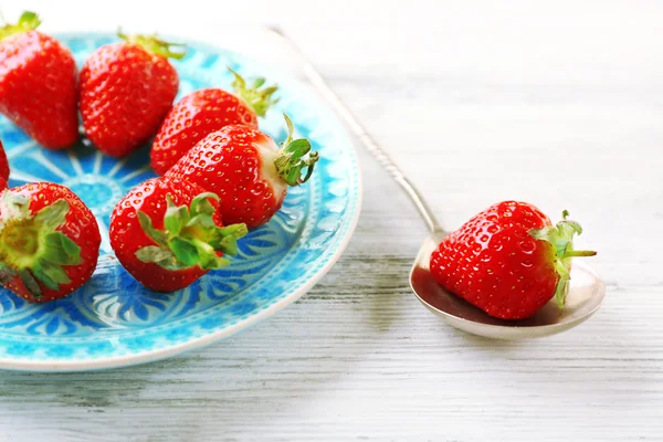 Strawberries on color plate, on color wooden background — Stock Photo, Image