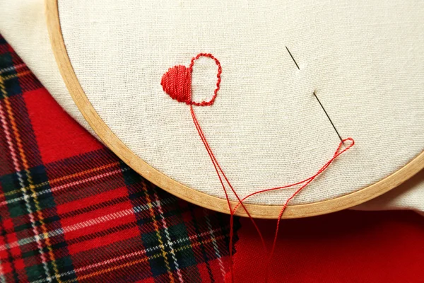 O aro de bordado com lona e fios de costura vermelho na mesa de perto — Fotografia de Stock