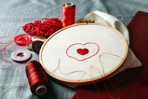 The embroidery hoop with canvas and red sewing threads on table close up — Stock Photo, Image