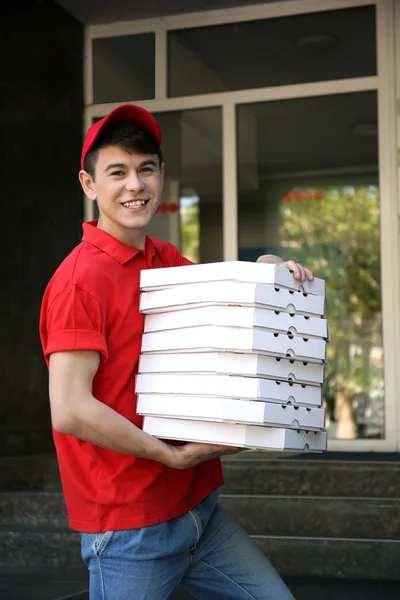 Jovem entregando caixa de pizza perto de casa — Fotografia de Stock