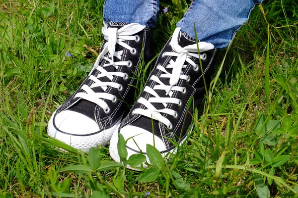 Pies femeninos en zapatos de goma sobre fondo de hierba verde —  Fotos de Stock