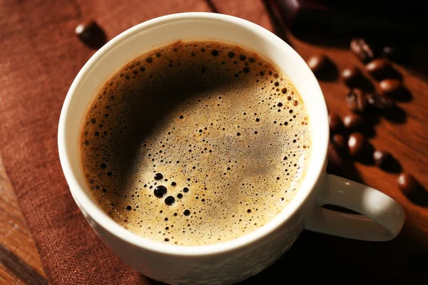 Cup of fresh coffee with beans on table, closeup — Stock Photo, Image