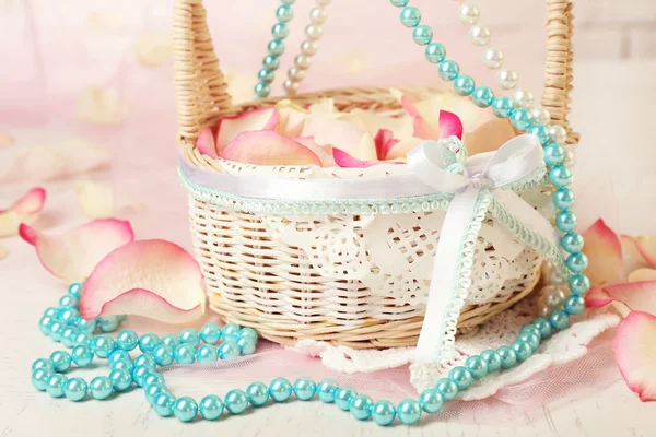 Cesta de boda con pétalos de rosas en la mesa, sobre fondo claro — Foto de Stock