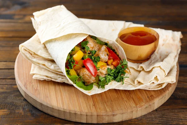 Homemade tasty burrito with vegetables on cutting board, on wooden background — Stock Photo, Image