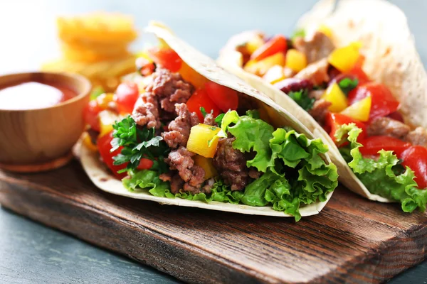 Burritos caseros de ternera con verduras y tortilla, sobre tabla de cortar, sobre fondo de madera — Foto de Stock