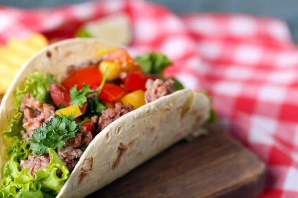 Hemgjord nötkött burrito med grönsaker, potatis chips på skärbräda, på trä bakgrund — Stockfoto