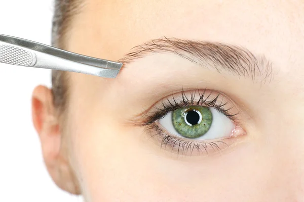 Mujer joven arrancando las cejas con pinzas de cerca — Foto de Stock