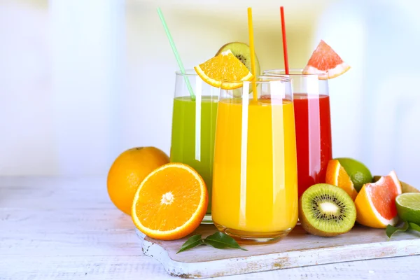 Glasses of different juice with fruits and mint on bright background — Stock Photo, Image