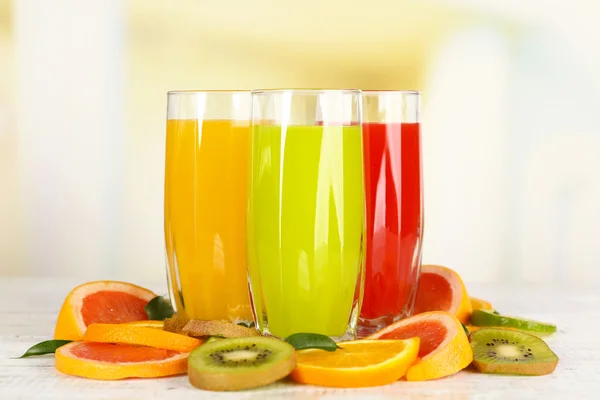 Óculos de suco diferente com frutas e hortelã em fundo brilhante — Fotografia de Stock
