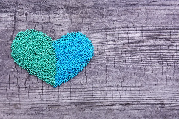 Cuentas coloridas en forma de corazón sobre fondo de madera —  Fotos de Stock