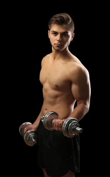 Νεαρός άνδρας μυών κρατώντας αλτήρες σε σκούρο φόντο — Φωτογραφία Αρχείου