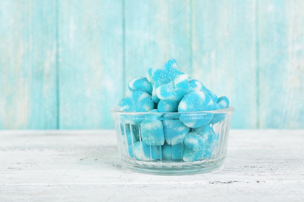 Blue candies in glass saucer on wooden background
