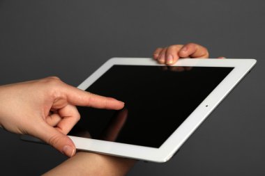 Tablet gri arka plan üzerinde tutan eller