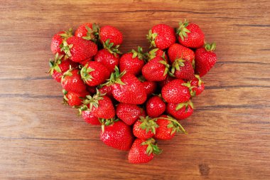 Ripe strawberries heart shaped on wooden background
