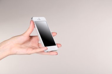 Mobil akıllı telefon gri arka plan üzerinde tutarak el