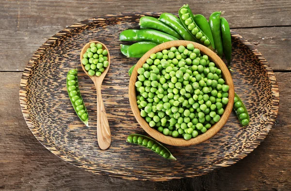 Pois verts frais dans un bol sur un plateau en bois, vue sur le dessus — Photo