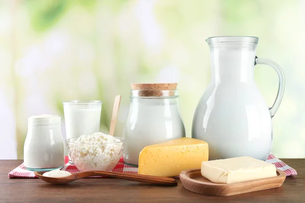 Dairy products on wooden table, on green nature background — Stock Photo, Image