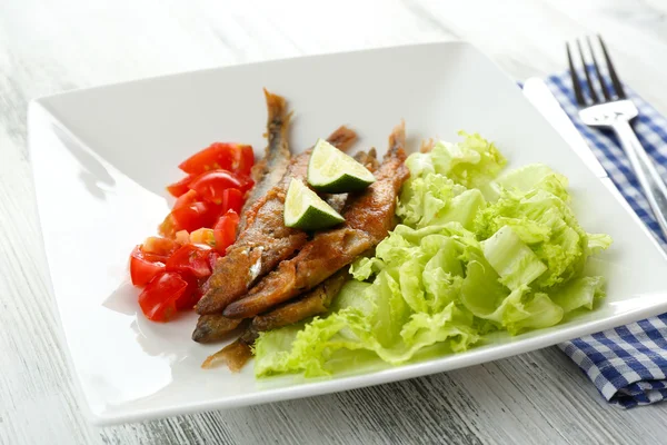 Petit poisson frit avec légumes sur la table gros plan — Photo