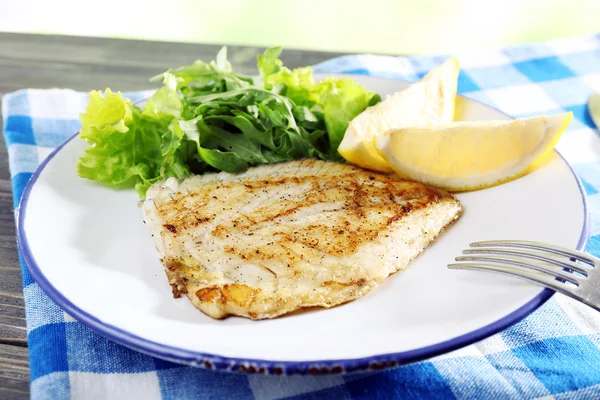 Plato de filete de pescado con lechuga y limón en la mesa de cerca — Foto de Stock