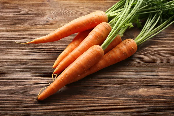 Zanahorias orgánicas frescas con tapas verdes sobre fondo de madera —  Fotos de Stock