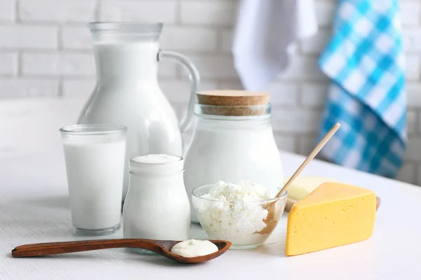Dairy products on wooden table, on brick wall background — Stock Photo, Image