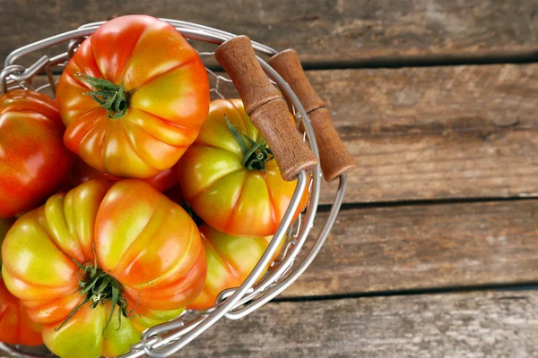 Groene tomaten in mand op houten achtergrond — Stockfoto