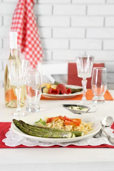 Gebratener Spargel und leckere Pasta mit Gemüse auf Teller auf Holztischhintergrund — Stockfoto