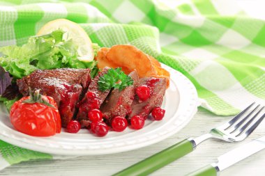 kızılcık sosu ve renk ahşap arka plan üzerinde plaka üzerinde kavrulmuş sebze ile lezzetli kavrulmuş et