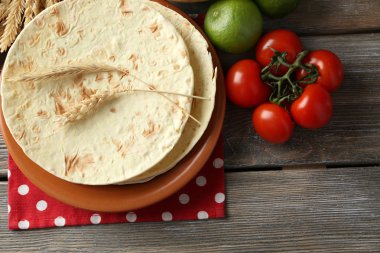 ev yapımı kepekli un tortilla ve ahşap masa arka plan üzerinde plaka üzerinde sebze yığını