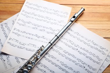 Ahşap masa üzerine müzik notlar ile gümüş flüt yakın çekim