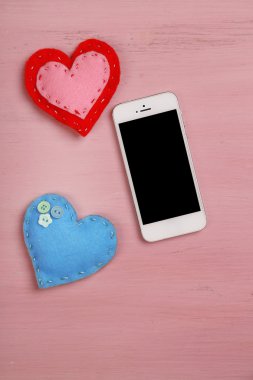 ahşap masa üzerinde yürekleri beyaz akıllı telefon.