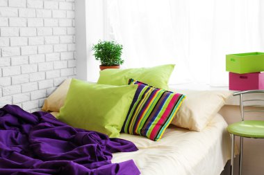 Comfortable bed with colorful pillows and purple blanket in bedroom clipart
