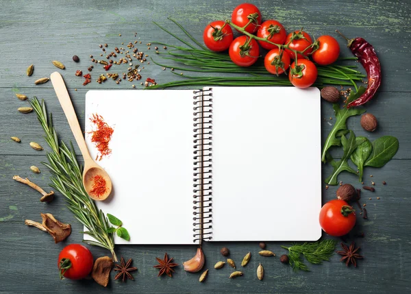 Offenes Rezeptbuch mit frischen Kräutern, Tomaten und Gewürzen auf Holzgrund — Stockfoto