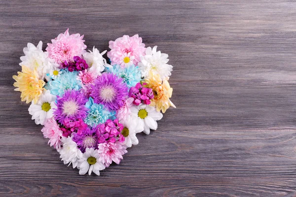 Schöne Blumen in Herzform auf Holzgrund — Stockfoto