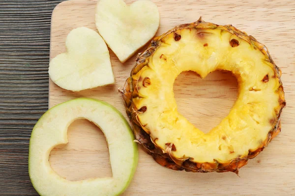 Fruits slices with cut in shape of heart on wooden background — Stock Photo, Image