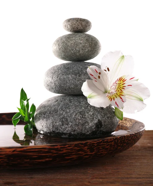 Piedras balnearias con alstroemeria y bambú en bandeja de madera con agua aislada sobre blanco —  Fotos de Stock