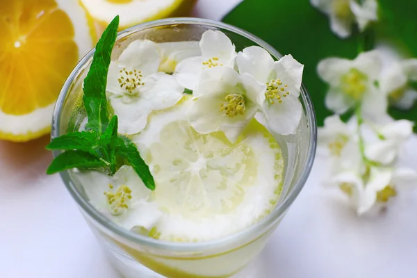 Soğuk ferahlatıcı yaz içeceği nane ile bardak ve masada limon dilimleri kapat — Stok fotoğraf