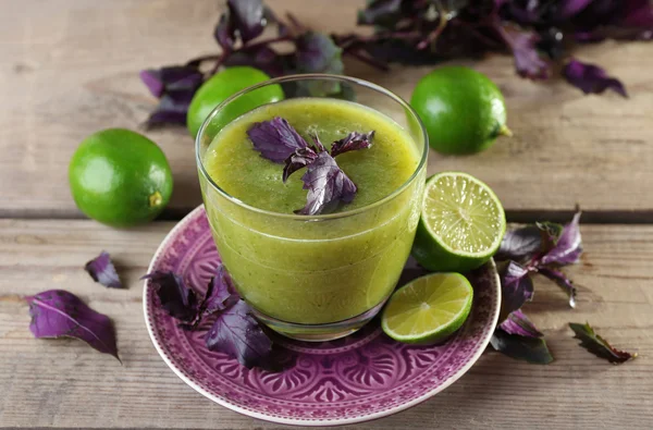 Vaso de jugo verde saludable con albahaca y limas en la mesa de cerca — Foto de Stock