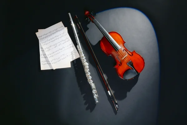 Violon et flûte avec notes de musique sur fond sombre — Photo