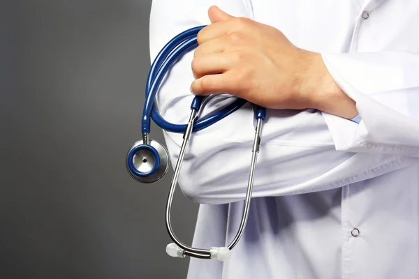 Arzt hält Stethoskop auf grauem Hintergrund — Stockfoto