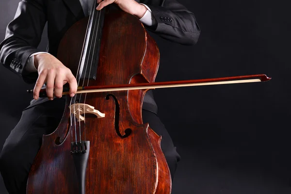 Uomo che suona il violoncello su sfondo scuro — Foto Stock