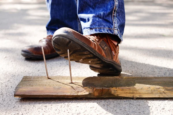 Worker steps on nail outdoors — Stock Photo, Image