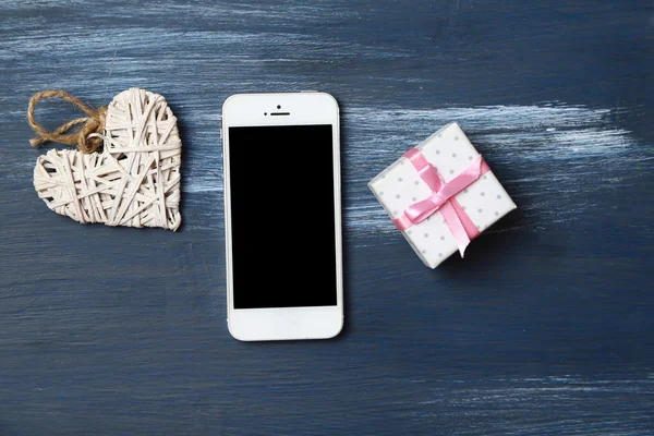 Weißes Smartphone mit Herzen auf Holztisch. — Stockfoto