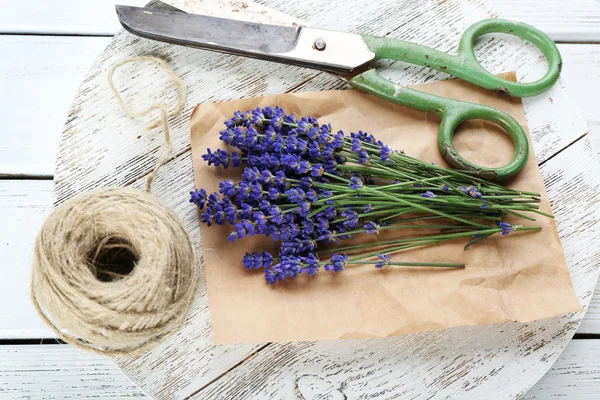 Fresh lavender with rope and scissors on parchment on wooden table, closeup — Stock Photo, Image
