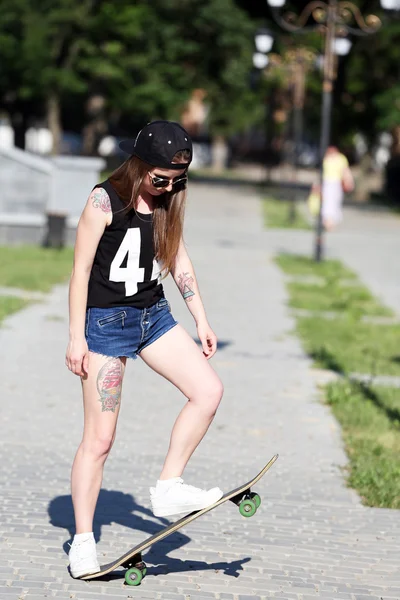 Mooie getatoeëerd meisje met skateboard, buitenshuis — Stockfoto