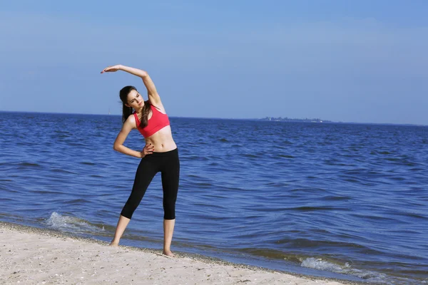 Νεαρή γυναίκα σπορ που κάνει άσκηση στην παραλία — Φωτογραφία Αρχείου