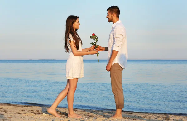 Joven hombre dando flores para su novia en la playa —  Fotos de Stock