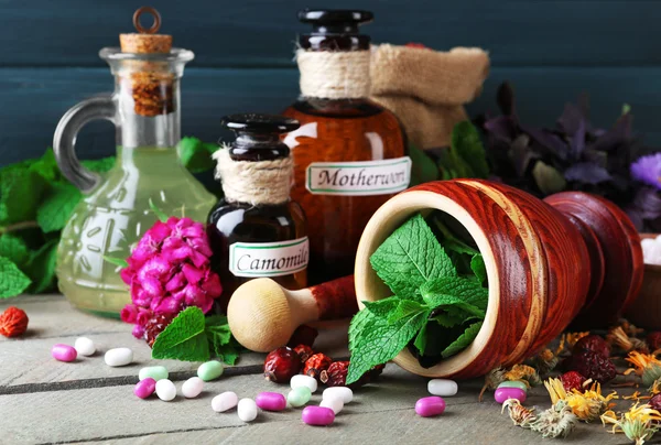 Kruiden, bessen, bloemen en pillen op een houten tafel achtergrond kleur — Stockfoto