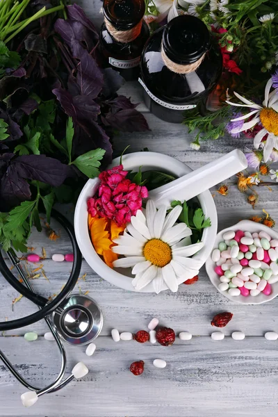 Альтернативная медицина травы, ягоды и стетоскоп на фоне деревянного стола — стоковое фото