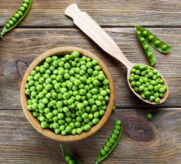 Guisantes verdes frescos en tazón y cuchara en la mesa de cerca —  Fotos de Stock